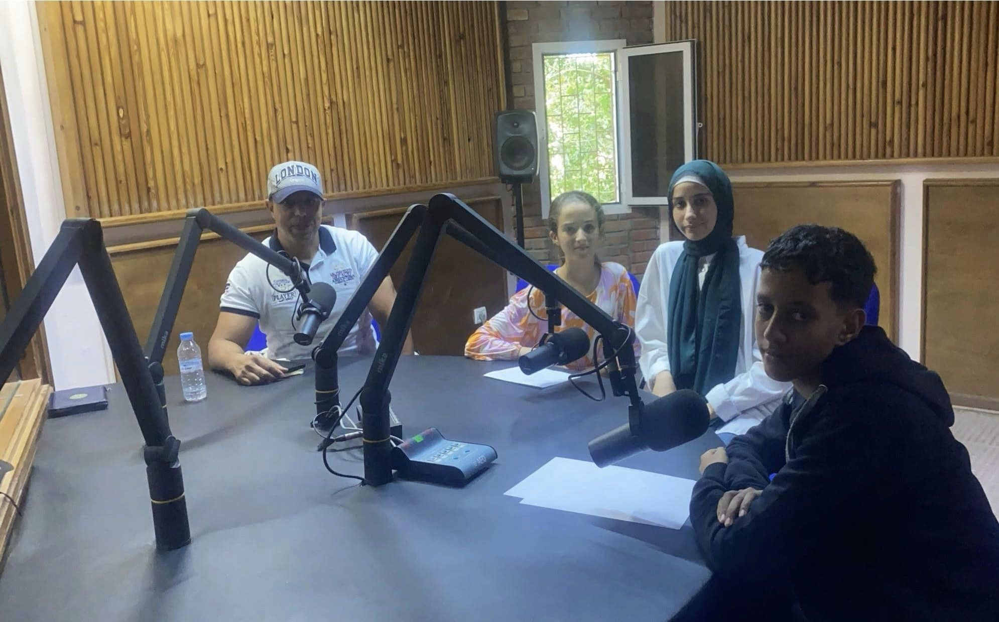 mr abdelilah poses with his students being interviewed for the radio