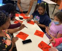 On the station of Chinese painting and calligraphy, students from lower grades and Spanish classes were writing Chinese characters with brush on red Xuan paper. 
